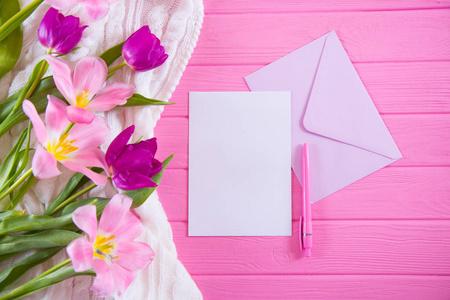 在粉红色的木质背景下, 用钢笔和信封和美丽的郁金香的嫩花束清晰的白纸纸
