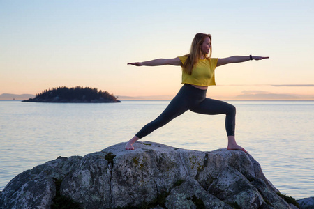 年轻女子在一个充满活力的日落的岩石岛上练习瑜伽。Whytecliff 公园, 马蹄湾, 西温哥华, 不列颠哥伦比亚省, 加拿大