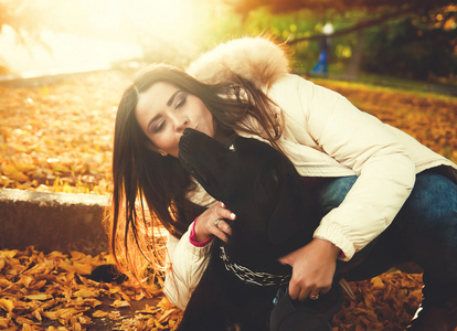 漂亮的年轻姑娘和一条狗公园里玩