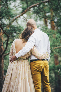 情侣抱着对方, 看着在米色美丽的礼服白色衬衫和黄色长裤秃头的性质