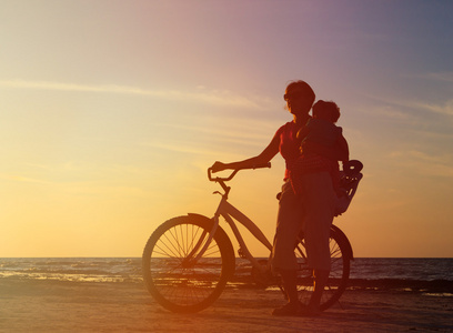 妈妈和骑自行车在日落时的剪影