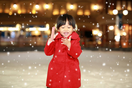 快乐笑蹒跚学步的女孩穿着一件红色的夹克有着一段有趣的雪，冬天的时候