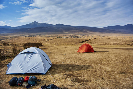 一座荒凉的山风景区的白色和红色橙色生动的帐篷