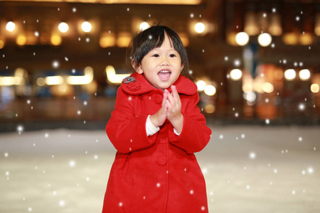 快乐笑蹒跚学步的女孩穿着一件红色的夹克有着一段有趣的雪，冬天的时候