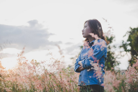 女人看着远处, 站在田野上日落背景