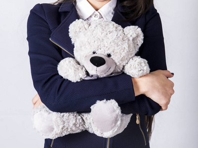 泰迪熊玩具在女孩的手在白色衬衣和深蓝色夹克