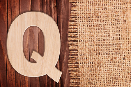 木制字母字母符号Q。在木桌背景王氏麻布