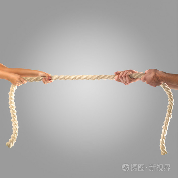 在灰色的背景上用力拉绳子的人的手里.竞争理念
