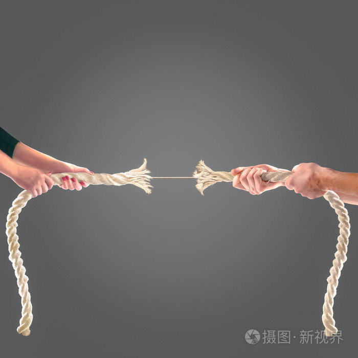在黑色背景上用力拉绳子的人的手里.竞争理念