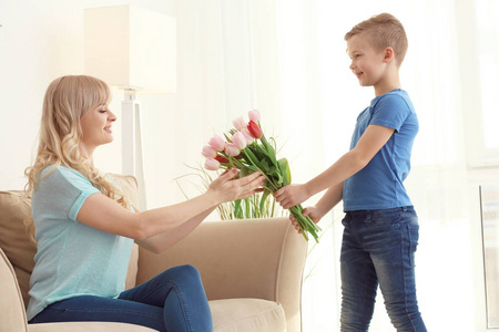 可爱的小男孩在家给他的母亲郁金香花束