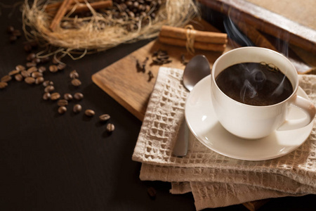 一杯咖啡与烟黑烤咖啡谷物和肉桂。对木材的背景。顶视图和框架题字