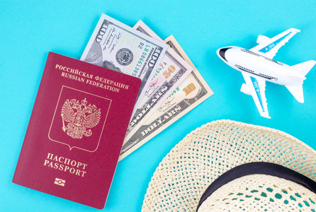 飞机帽和红色俄罗斯护照与美元在蓝色背景。旅游理念