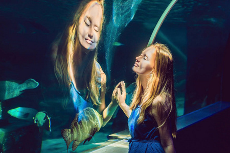 年轻女子看着隧道水族馆的鱼图片