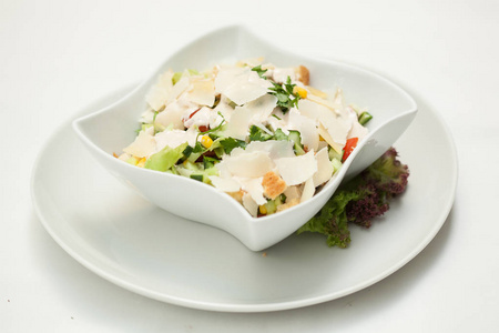 在白色背景上的白色碗中混合蔬菜沙拉