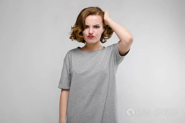美丽的红发女孩的肖像愁眉苦脸的灰色背景