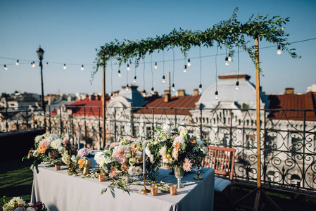 长餐桌上覆盖着白色的布, 配有瓷器和蓝色的眼镜, 还有华丽的花饰, onroof 站在房子里。