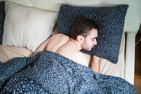 年轻男子在家里的床上休息的睡眠跟踪器