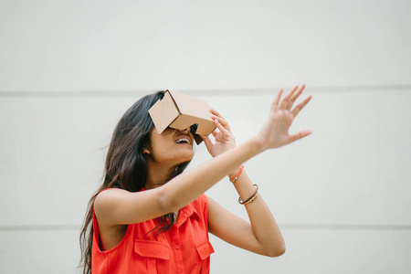 一位年轻而上镜的印度女性首次尝试虚拟现实护目镜。她笑着笑着高兴和惊讶的经验