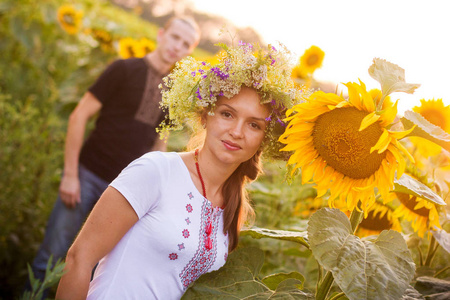 年轻美丽的恩爱的夫妻在日落时分走在盛开的向日葵一个领域的国家乌克兰衬衫
