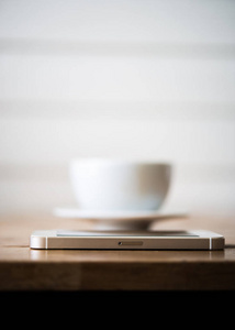 咖啡馆里的木桌上有一杯咖啡和智能手机。咖啡湾