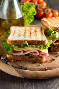 俱乐部三明治的特写照片。三明治与满足, 意大利火腿, 意大利腊肠, 沙拉, 蔬菜, 生菜, 西红柿, 洋葱和芥末在一个新鲜切片黑