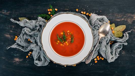 番茄汤配辣椒和蔬菜。健康食品。在黑色的木质背景。顶部视图。复制文本的空间