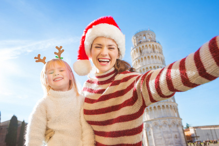 妈妈带着圣诞帽和女儿在比萨自拍