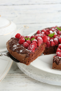 一块蛋糕巧克力釉与覆盆子色木背景