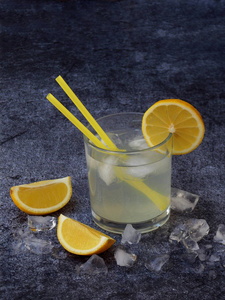 眼镜的柠檬片，冰块和秸秆在深色背景上的冷自制柠檬水。复制空间