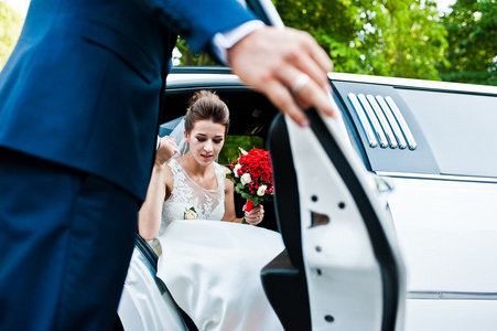 新郎的豪华轿车扇敞开的门，牵着新娘的手
