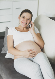 幸福的怀孕女人坐在沙发上放松 聊天的肖像