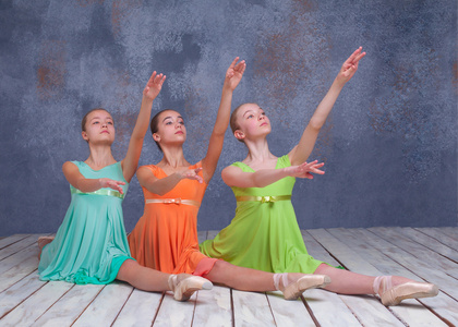 三个年轻的芭蕾舞演员摆在地板上