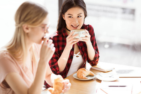 女孩吃牛角面包，喝咖啡