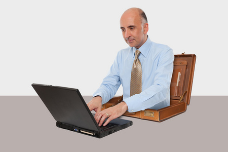 商人在办公桌前工作与他的笔记本电脑