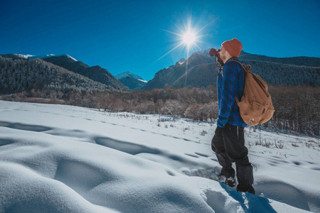 在山里徒步旅行，背包里的人。寒冷的天气，山上的雪。冬季徒步旅行。太阳和雪