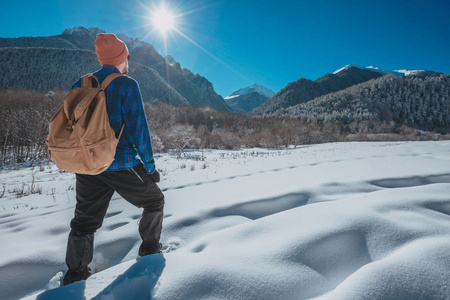 在山里徒步旅行，背包里的人。寒冷的天气，山上的雪。冬季徒步旅行。太阳和雪