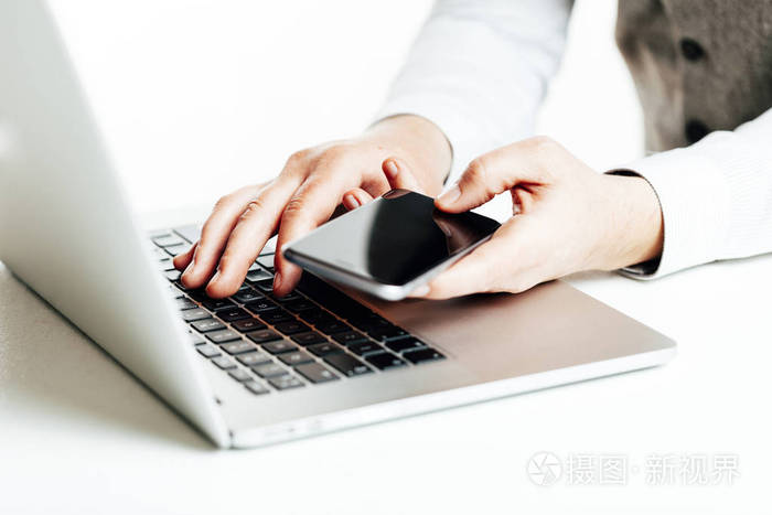 关闭使用一台笔记本电脑和手机的多任务处理商务人的形象