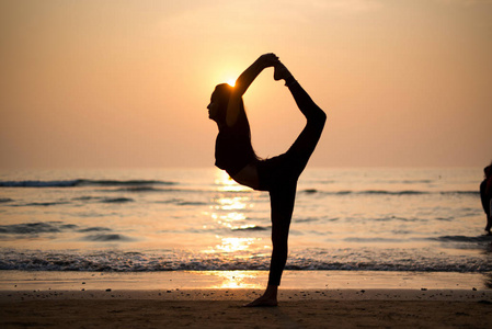 ung frisk kvinna utvar yoga p stranden vid solnedgngen