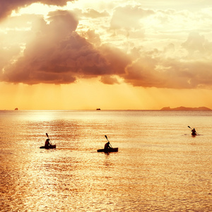 三皮划艇浮在日落时