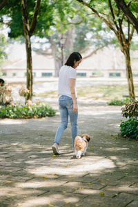 一个年轻的泛亚洲妇女的肖像坐在她年轻的石 tzuh 小狗在公园里的一天。她在微笑, 他们都在享受温暖的一天。