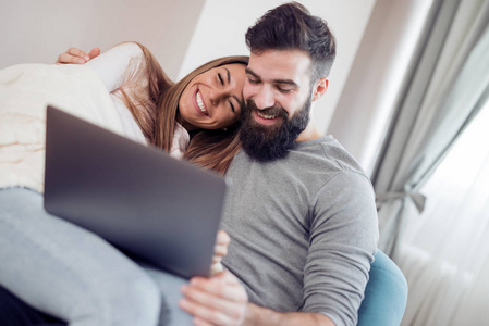 爱, 家庭, 技术, 互联网和幸福概念在家中带膝上型电脑的微笑快乐情侣