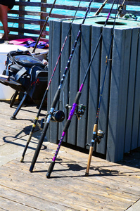 钓鱼竿和卷轴靠在鱼的清洁容器上。在戴尼亚海滩钓鱼码头一个热门的地方为体育渔民的预算