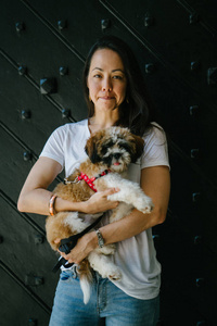 一个年轻的女孩和她的狗的肖像。泛亚洲女人很有魅力, 穿着随意, 带着她的 Tzuh 在怀里, 轻轻地微笑着。