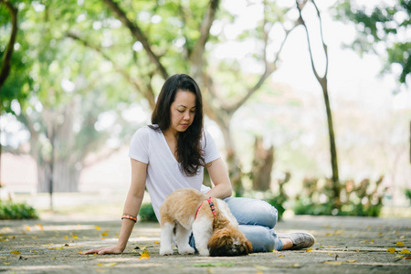 一个年轻的泛亚洲妇女的肖像坐在她年轻的石 tzuh 小狗在公园里的一天。她在微笑, 他们都在享受温暖的一天。