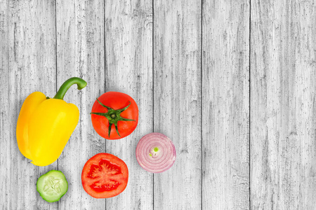 蔬菜混合在老木背景上。鲜黄色辣椒, 切碎的西红柿, 洋葱, 圆黄瓜切片。健康生活方式的概念。素食
