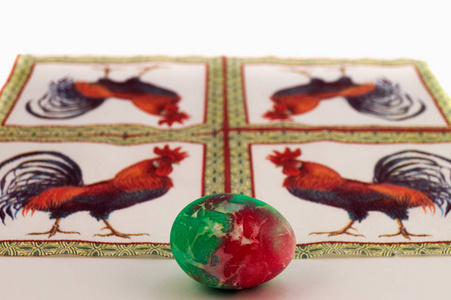 在红色, 绿色色调与离婚的背景下, 一张有公鸡图片的餐巾画复活节彩蛋