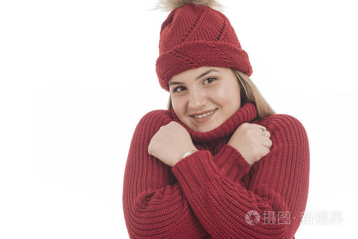 美丽的微笑的女孩在温暖的红色毛衣和红色帽子