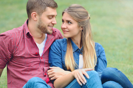 浪漫夫妇坐在草地上，看看对方的眼睛