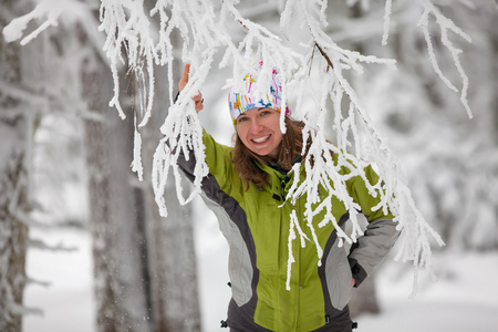 年轻女子在冬季山区的相机摆姿势