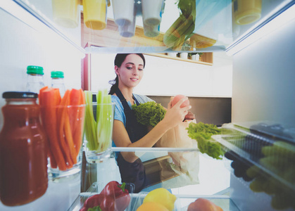 女性站附近打开冰箱充分的健康食品，蔬菜和水果的画像。女性肖像